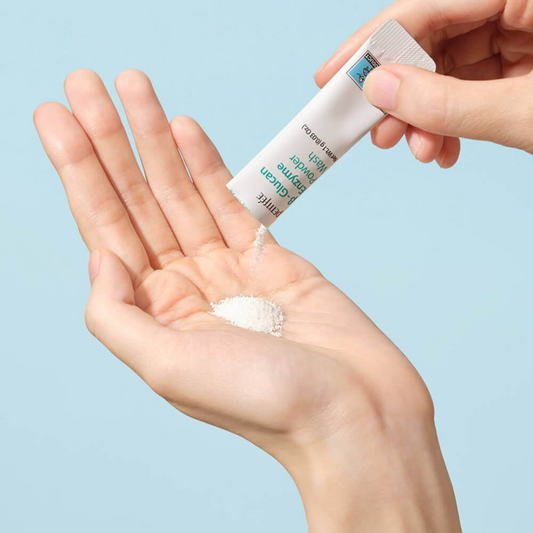 Bilde av en som heller litt av Petitfee B-Glucan Enzyme Powder Wash i hånden. Viser at konsistensen til produktet er som pudder.