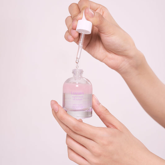 Bilde av en som åpner Luvum slow aging oil serum og viser applikatoren og konsistensen på produktet.