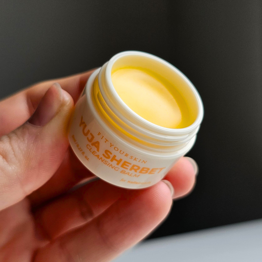 Bilde av en som holder en åpnet krukke med Yuja Sherbet Oljerens fra Fit Your Skin i reisestørrelse