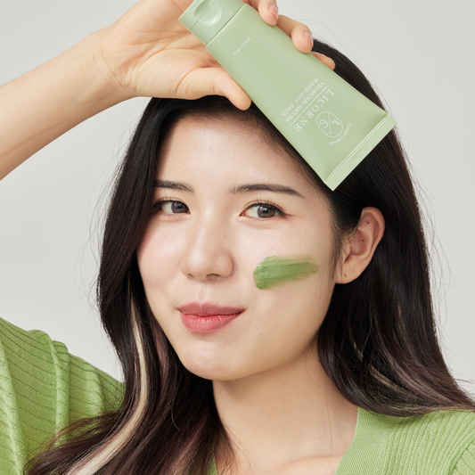 Bilde av dame med Licorne Matcha Wash off mask i ansiktet mens hun holder produktet i hånden