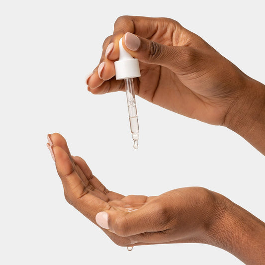 Bilde av dame som bruker applikatoren til The Potions Tea Tree Oil Serum for å dryppe dråper i håndflaten 